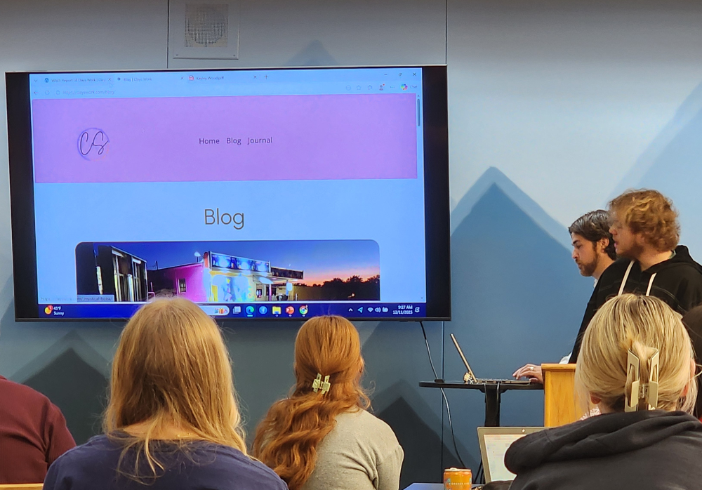 Clayton Smith presenting his internship presentation with Justin Wood helping in the background.